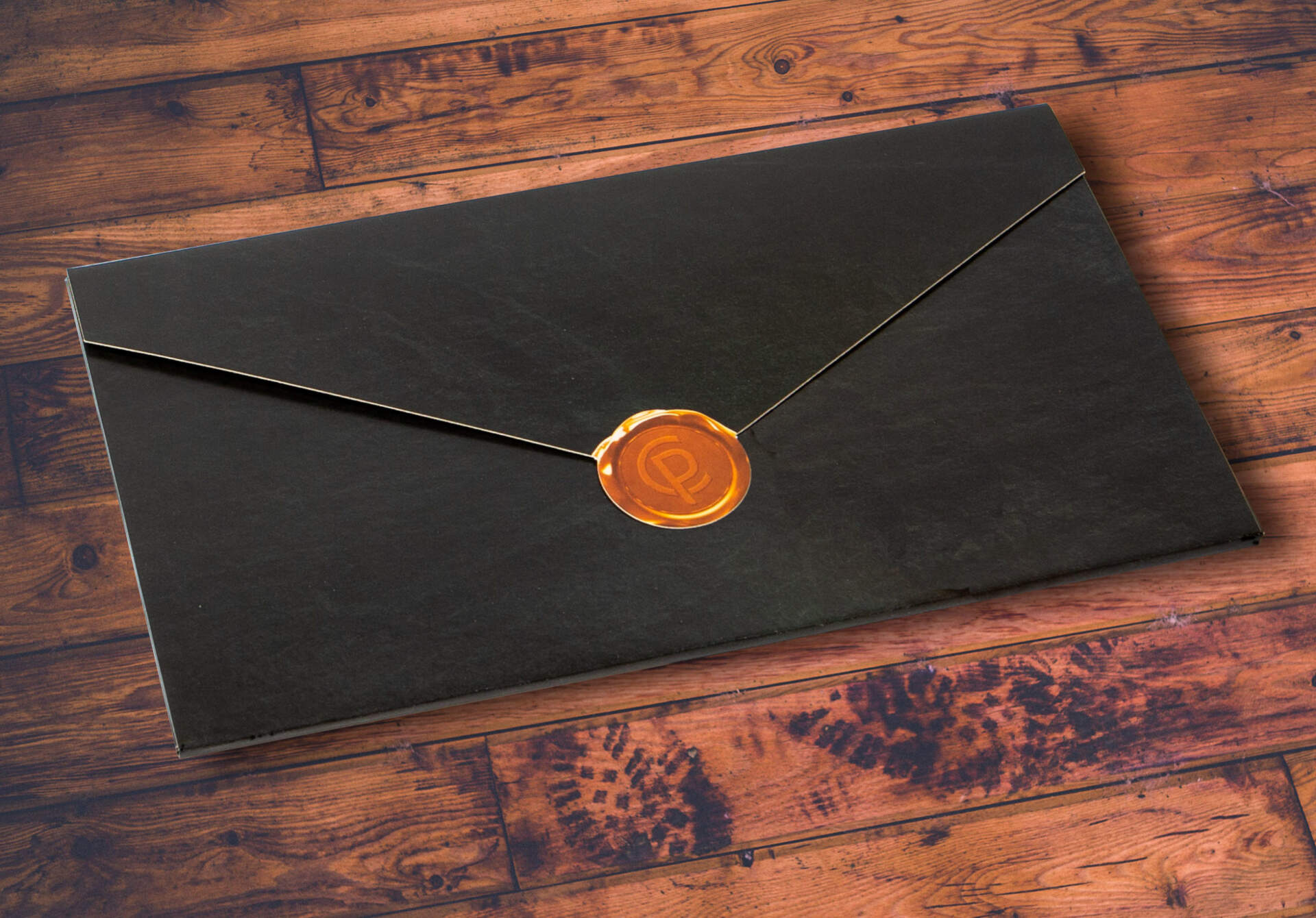 Closed business to business mailer with classy style and orange diecut seal on wooden table